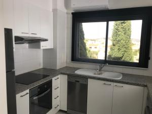 a white kitchen with a sink and a window at Olosuites in Limassol
