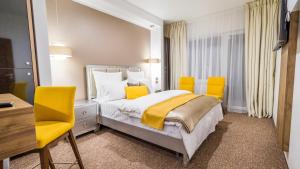 a bedroom with a bed and two yellow chairs at Dumbrava Residence in Sibiu