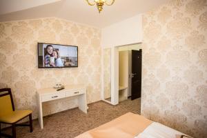 a hotel room with a television on the wall at Hotel-Restaurant Ayan Piatra Neamt in Piatra Neamţ