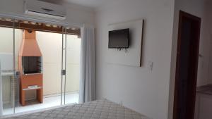 1 dormitorio con 1 cama y TV en la pared en Condomínio Mont Carmelo - Apto 24 B, en Porto Seguro