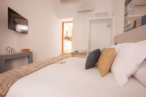 een slaapkamer met een wit bed met kussens en een televisie bij Lukanda Mariana in Sevilla