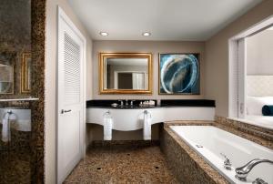 
a bathroom with a tub, sink and mirror at Fairmont Vancouver Airport In-Terminal Hotel in Richmond
