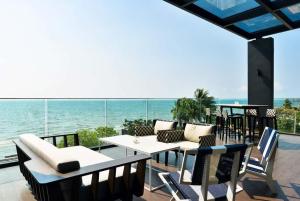 un patio con mesa, sillas y el océano en Veranda Residence Pattaya x Sea & Sky View en Na Jomtien