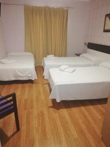 a hotel room with three beds and a wooden floor at Hotel Gardu in Montealegre del Castillo