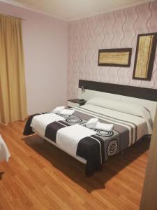 a bedroom with two beds with white and black sheets at Hotel Gardu in Montealegre del Castillo