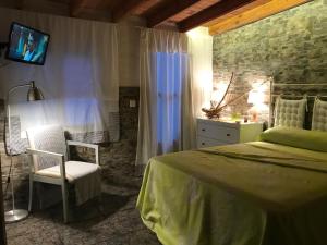 een slaapkamer met een bed, een stoel en een televisie bij Casa con encanto en Calabardina, cerca de la playa in Calabardina
