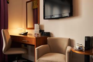 a hotel room with a chair and a desk and a television at Heywood House Hotel, BW Signature Collection in Liverpool