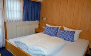 a white bed with blue and white pillows on it at Haus Tschiderer in Kappl