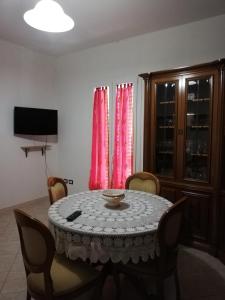 ein Esszimmer mit einem Tisch mit Stühlen und rosa Vorhängen in der Unterkunft LOCAZIONE TURISTICA " Su Passizzeri " in Suni