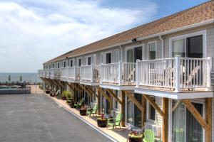 a building with a balcony with chairs and tables at The Corsair & Cross Rip Oceanfront in Dennis Port