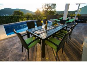 Une table à manger et des chaises sont disponibles sur la terrasse. dans l'établissement Villa Croatia Sea View with heated pool, à Vinišće