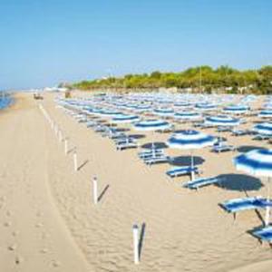 kilka krzeseł i parasoli na plaży w obiekcie Tenuta Crescentini-ValleMura ,appartamenti con entrata indipendente w mieście San Donà di Piave