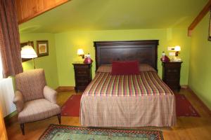 ein Schlafzimmer mit einem Bett mit einem roten Kissen und einem Stuhl in der Unterkunft Hotel Cenera in Cenera