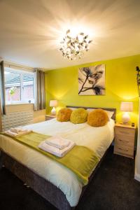 Ripley Peak District Gateway في ريبلي: غرفة نوم مع سرير بجدران صفراء وثريا