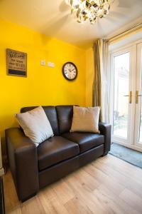 a brown leather couch in a living room with a clock at Ripley Peak District Gateway in Ripley