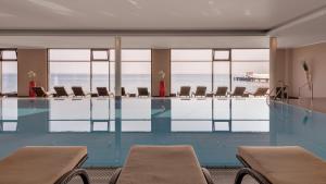 a swimming pool with chairs and the ocean in the background at Bayside in Scharbeutz