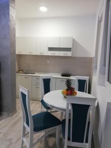 a kitchen with a white table and chairs with a bowl of fruit on it at Airport view Apartment in Belgrade