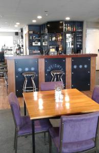 a dining room with a wooden table and purple chairs at Catlins Inn in Owaka