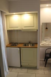 una pequeña cocina con armarios blancos y fregadero en Vasilikos Studios, en Naxos Chora