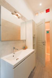 La salle de bains blanche est pourvue d'un lavabo et d'un miroir. dans l'établissement Spartacus Inn Apartment, à Rome