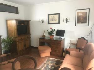 een woonkamer met een tv en een bureau met een computer bij Casa da 25 in Espinho