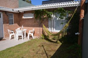 a patio with a table and chairs and a hammock at Aire Marino in Balneario Claromecó