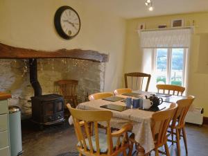 a dining room with a table and a clock on the wall at 1 Tan-y-castell in Dolwyddelan