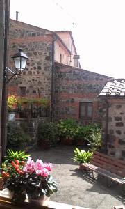 ein Backsteingebäude mit einer Bank und Blumen im Innenhof in der Unterkunft Casa del Ciliegio in Radicofani