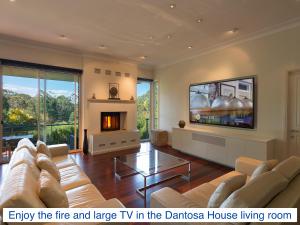 sala de estar con sofá, TV y chimenea en Dantosa Blue Mountains Retreat, en Katoomba