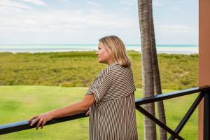 
a woman standing by a fence looking at the water at Moonlight Bay Suites in Broome
