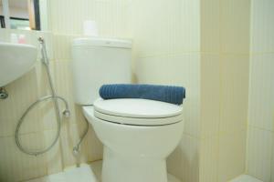 a bathroom with a toilet with a blue towel on it at Simply Studio Room at Annora Living Apartment Tangerang By Travelio in Tangerang