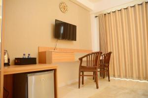 a room with a desk with a television and two chairs at Simply Studio Room at Annora Living Apartment Tangerang By Travelio in Tangerang