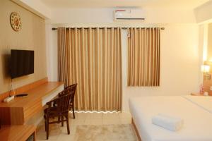 a hotel room with a bed and a desk and a television at Simply Studio Room at Annora Living Apartment Tangerang By Travelio in Tangerang +2 photos