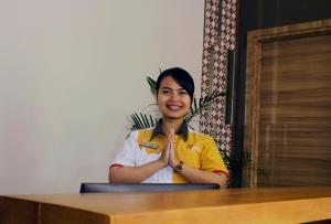 a woman is sitting at a table with her hands in front of a desk at Front One Cabin Malioboro Jogja in Yogyakarta