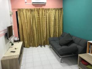 een woonkamer met een bank en een televisie bij Seri Manjung Homestay Wazer Residence in Lumut