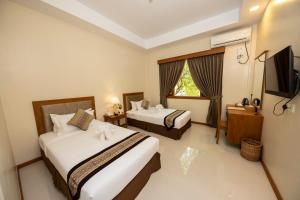 a hotel room with two beds and a flat screen tv at Bagan Sense Hotel in Bagan
