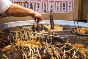 Eine Person kocht Essen auf einem Grill in der Unterkunft Sun Palace Hotel in Shizuoka