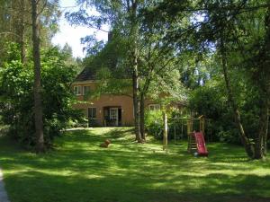 ein Haus mit einem Hof mit einem Spielplatz davor in der Unterkunft Pension 'Das kleine Landhaus' in Oberhaverbeck