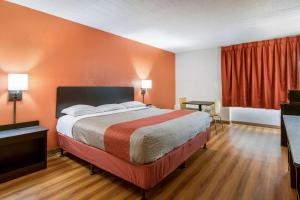 Cama grande en habitación con paredes de color naranja en Motel 6-New Stanton, PA en New Stanton