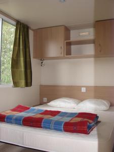 een bed met een deken erop in een slaapkamer bij Camping Moulin de Collonge in Saint-Boil