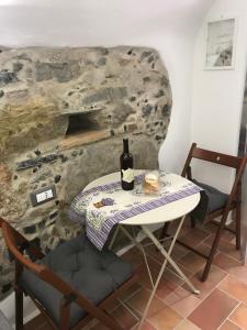 una mesa con una botella de vino junto a una pared de piedra en Le Ciappe Castelbianco Terra CITR 9020-BEB-0003 en Castelbianco