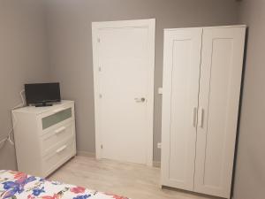 a bedroom with a white door and a bed and a dresser at Habitaciones en Ronda in Castro-Urdiales
