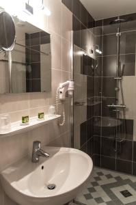 een badkamer met een wastafel en een douche met een spiegel bij Le Rhien Hôtel-Restaurant in Ronchamp