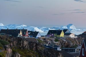 a village on a hill with snow covered mountains at Icefiord Apartments in Ilulissat