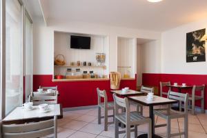 a restaurant with two tables and chairs and a red wall at The Originals Access, Hôtel Figeac in Figeac