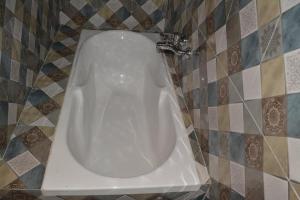 a white toilet in a bathroom with a tiled wall at Shalini Excellency in Mahabaleshwar