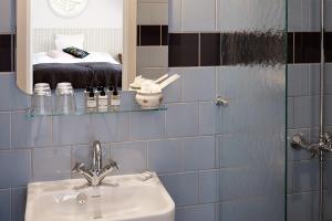 ein Bad mit einem Waschbecken und einem Spiegel in der Unterkunft Hotel Hornbækhus in Hornbæk