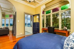 a bedroom with a bed and a desk and windows at Devonport Harbour View in Auckland