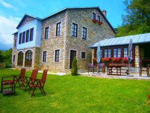 - un grand bâtiment en briques avec des chaises dans la cour dans l'établissement Argyro Guesthouse - Ξενώνας Αργυρώ, à Nymfaio