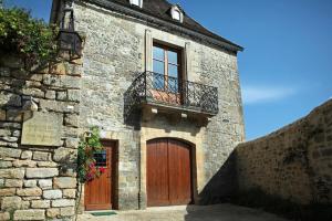 a stone building with two doors and a balcony at La Cafourche in Beynac-et-Cazenac